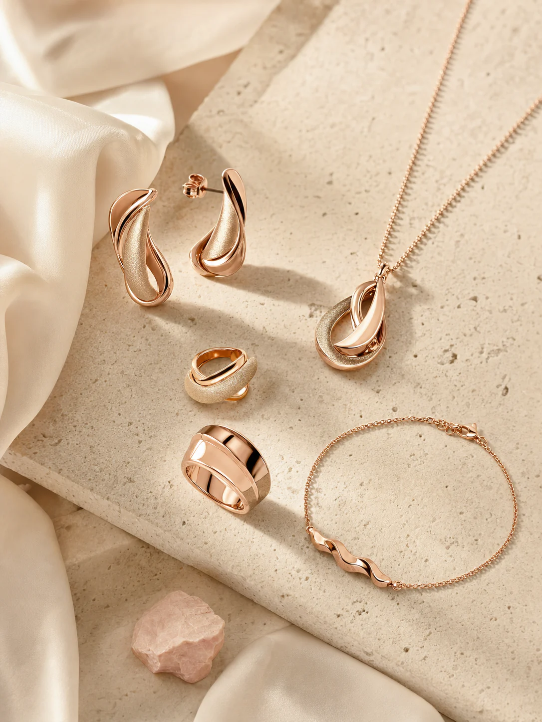Rose-gold jewelry collection on ivory stone and silk